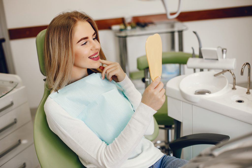 uśmiechnięta kobieta w gabinecie stomatologicznym